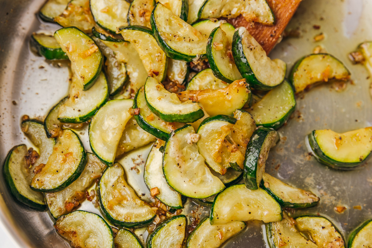 sauteed zucchini in a pan pushed with a wooden spatula.