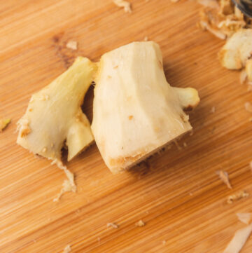 peeled ginger on a chopping board with the peelings.
