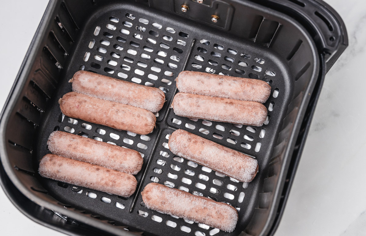 frozen sausages in air fryer basket.