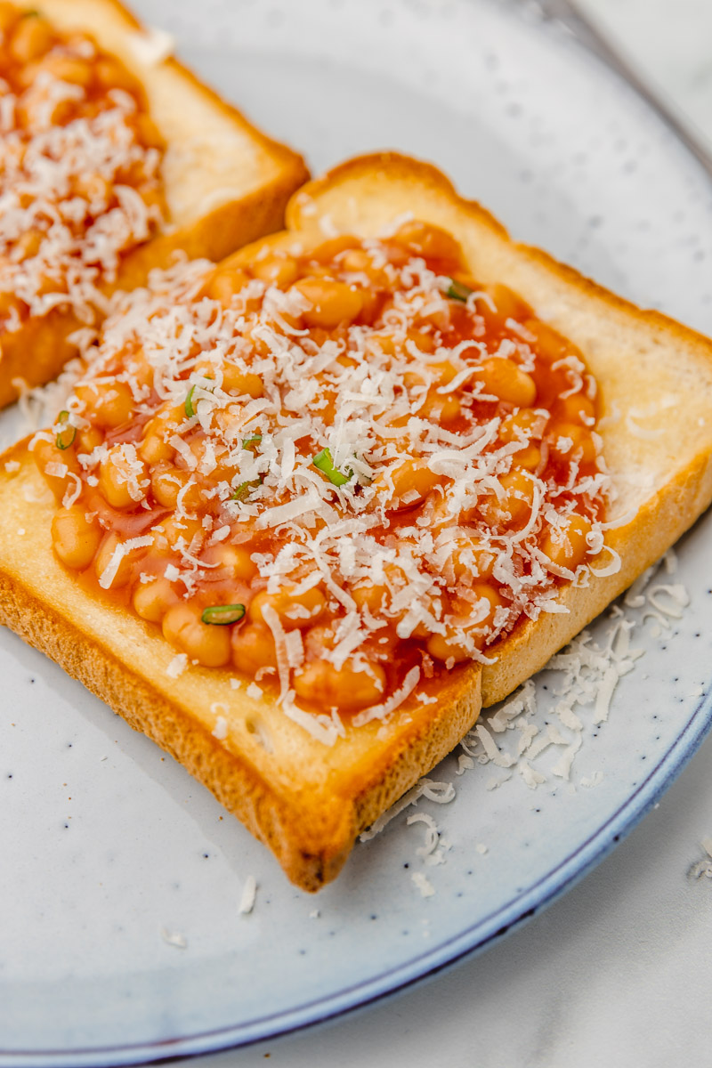 a close up on baked beans on toast with cheese. 
