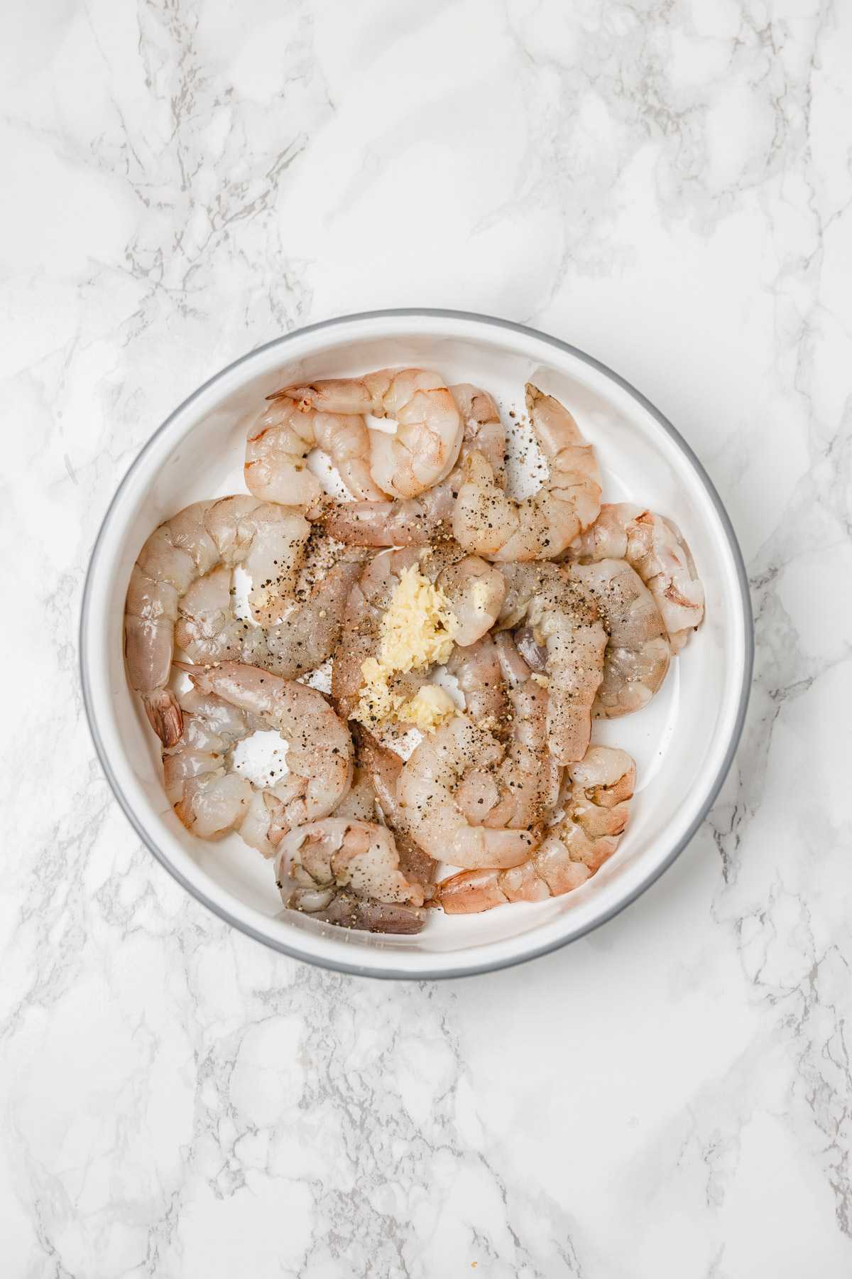 fresh shrimp in a baking dish with freshly minced garlic and black pepper.
