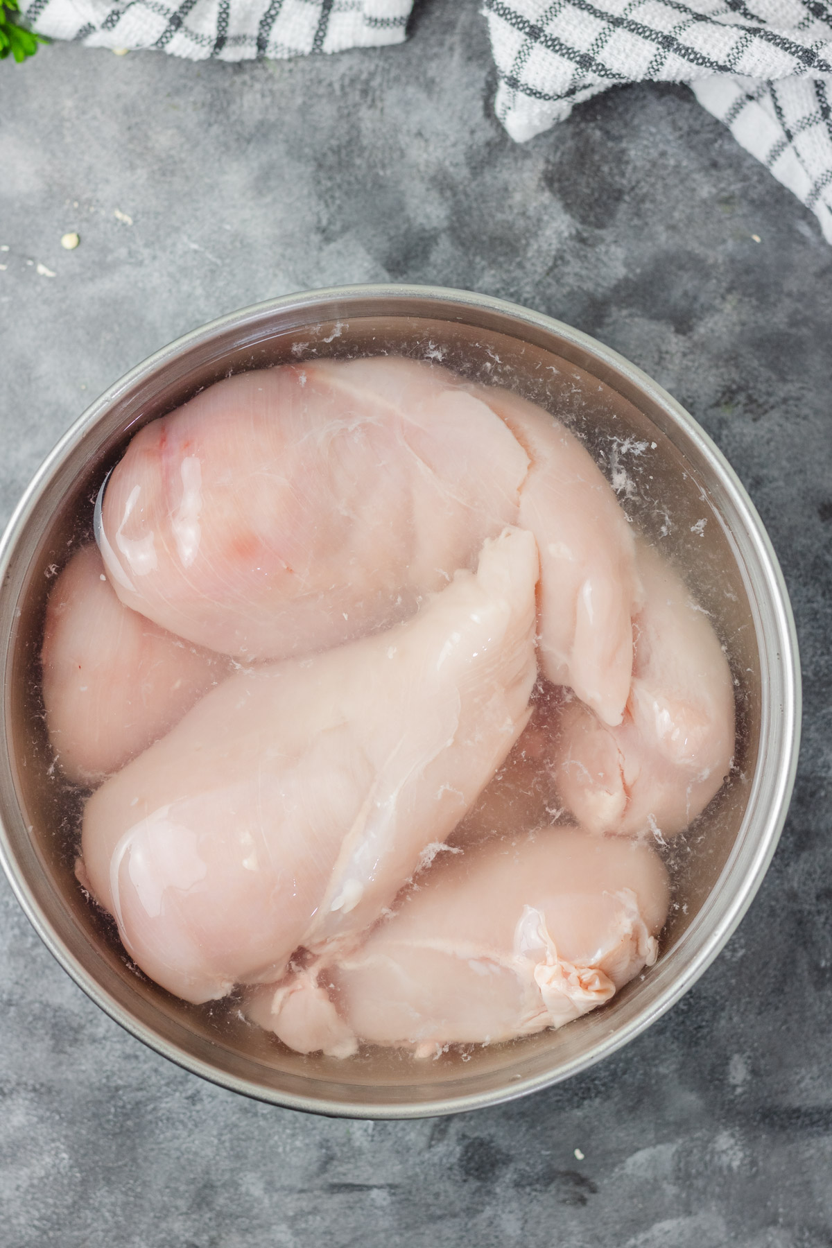 whole chicken breast brining in salt water solution.