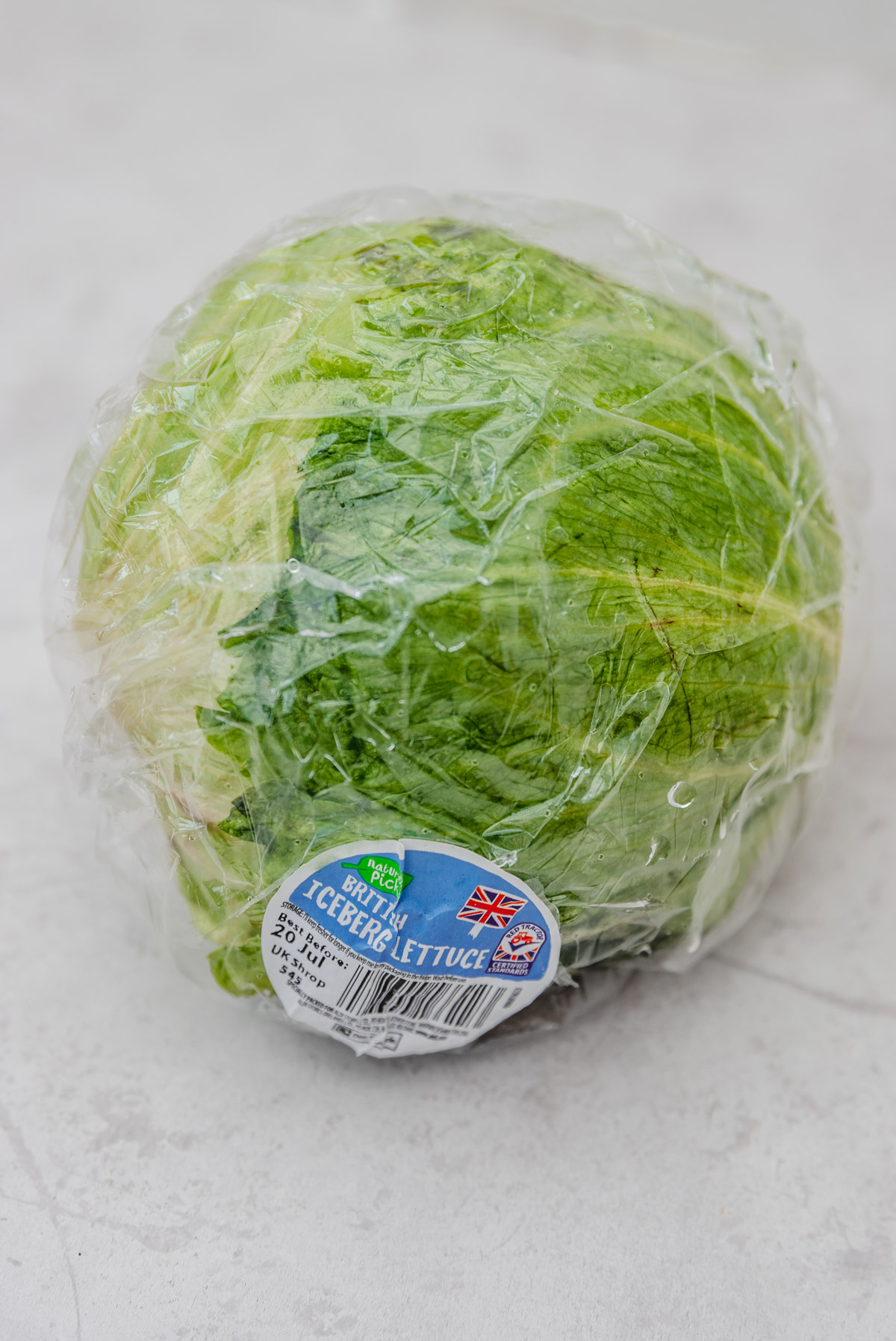 a head of iceberg lettuce in its original packaging with a label on it.